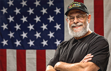 Happy Veteran smiling in front of the U.S. flag.